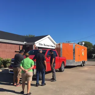 a group of people standing in front of a red truck