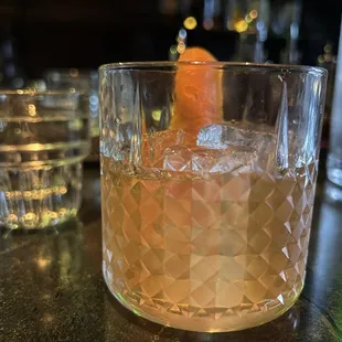 a drink in a glass with an orange garnish