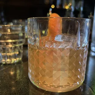 a drink in a glass with an orange garnish