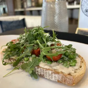 a sandwich with arugula and tomatoes
