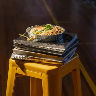 a bowl of noodles on a stack of books
