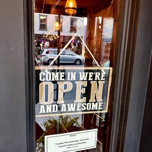 a sign that reads come in we're open and awesome