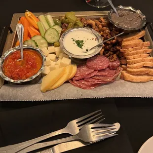 a platter of meats, cheeses, crackers, and vegetables