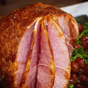 a ham on a platter with grapes