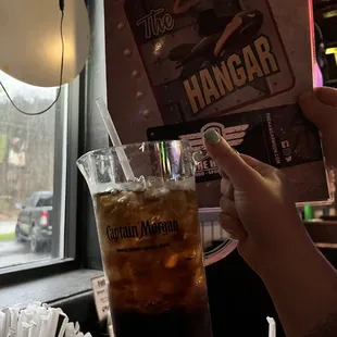 a person holding a drink in front of a menu