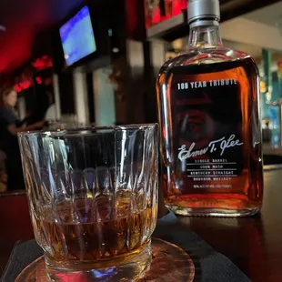 a glass of whiskey and a bottle of bourbon