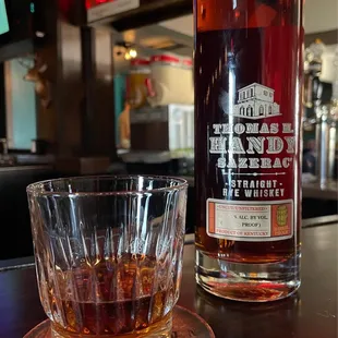 a glass of whiskey next to a bottle