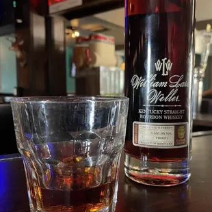 a glass of whiskey next to a bottle