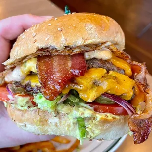 Double smash burger with smoked cheddar, bacon, pimento cheese, fried egg, lettuce, tomato, deli mustard, and Hayden sauce on a challah bun