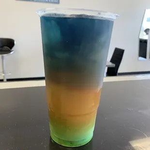a blue and yellow drink in a plastic cup