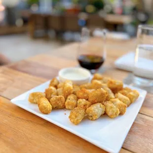 a plate of tater tots and a glass of wine