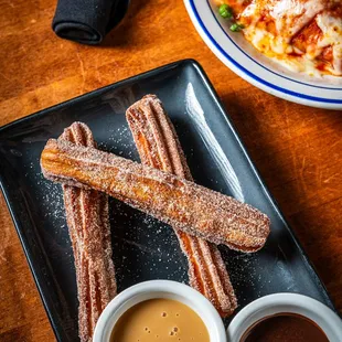 a plate of churros and dipping sauce