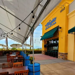 the outside of a restaurant with tables and chairs