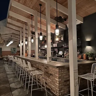 an outdoor bar with white chairs