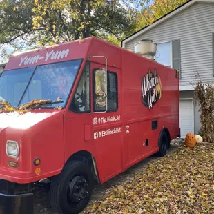 a red food truck parked in front of a house