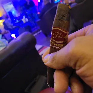 a hand holding a cigar