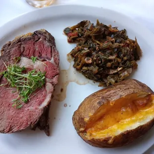 Prime rib with loaded baked potato and collard greens
