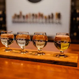 four glasses of beer on a wooden tray