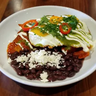 Beto&apos;s Chiliquiles - salsa verde y roja, sunny side up eggs, crema, avocado, cotija, cilantro, black beans