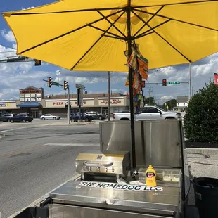 a hot dog cart with a yellow umbrella