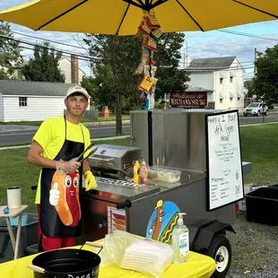 a man standing in front of a hot dog cart