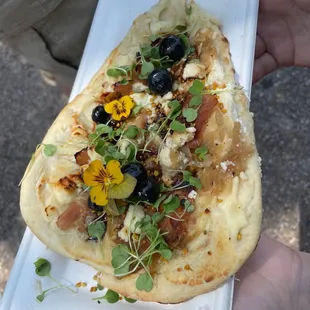 a hand holding a flatbread pizza