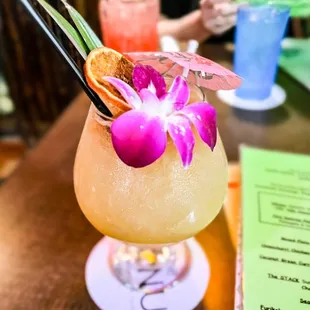 a tropical drink with a purple flower