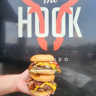 a hand holding a stack of hamburgers