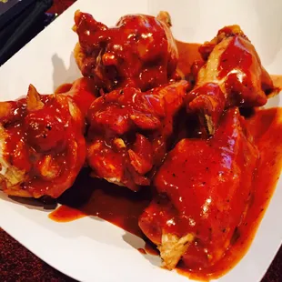 a plate of chicken wings covered in bbq sauce