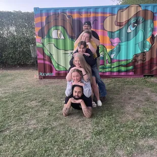 a family posing in front of a mural
