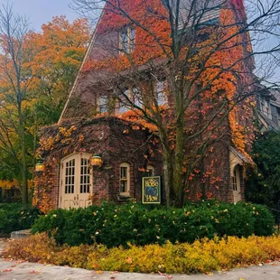 a brick house with autumn leaves on the ground