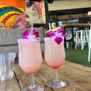 two pink cocktails on a wooden table