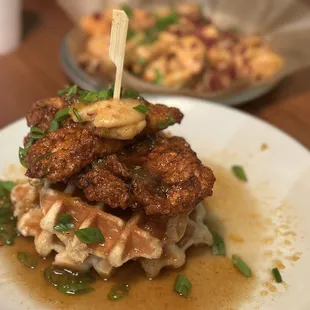 NASHVILLE STYLE CHICKEN 'N WAFFLES Crispy Chicken Tenders Nashville Style, Belgian Waffle, Peach Maple Syrup, Green Onion &amp; Compound Butter.