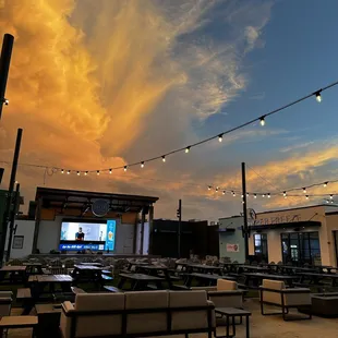a sunset view of a patio with tables and benches
