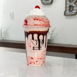 a strawberry milkshake with whipped cream and a cherry on top