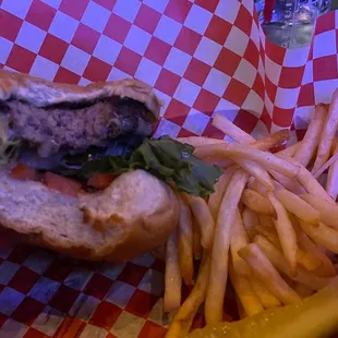 a hand holding a hamburger and fries