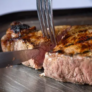 a piece of steak being cut with a knife and fork