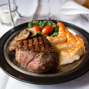 a plate of steak, potatoes, and shrimp