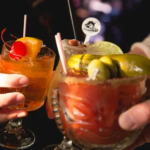 two people holding cocktails