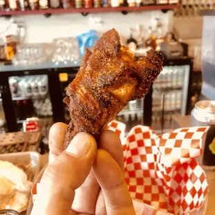 a hand holding a fried chicken