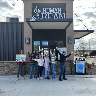 a group of people standing in front of a coffee shop