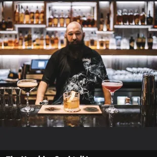 a man behind a bar with a drink