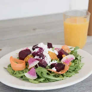 a plate of salad and a glass of orange juice