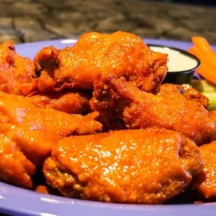 a plate of buffalo wings and carrots