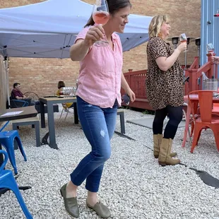a woman in a pink shirt and jeans playing a video game