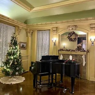 a living room with a piano and christmas tree
