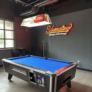 a pool table with a neon sign above it
