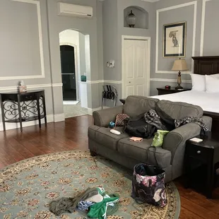 Spacious room with king sized bed, table, sofa and fireplace.