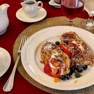 Brunch entree of French toast with berries, nuts, and creme anglaise.