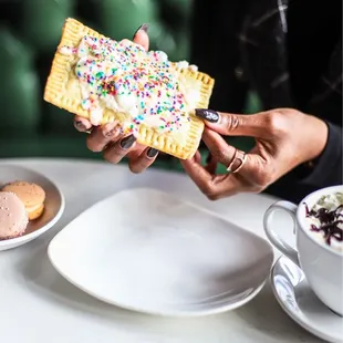 a person holding a pastry with sprinkles